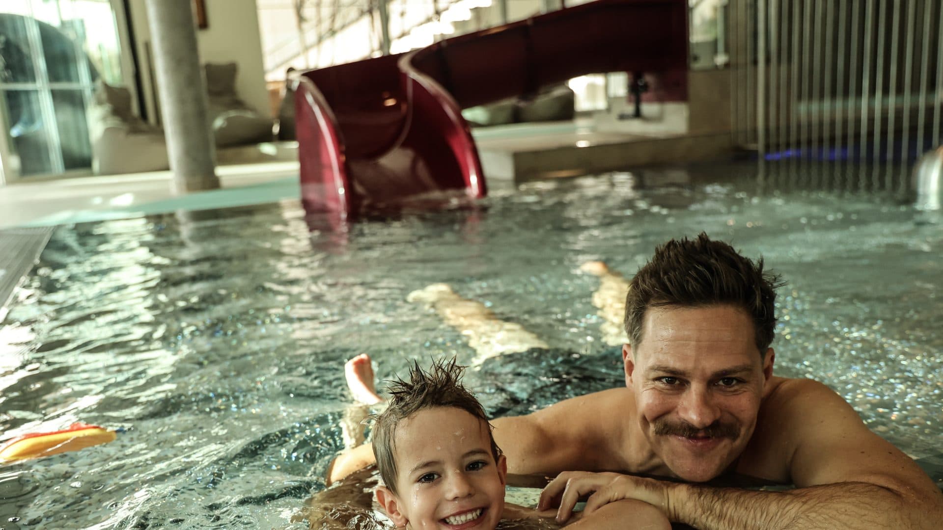 Vater und Kind beim Schwimmen im Wellnesshotel mit Wasserpark.