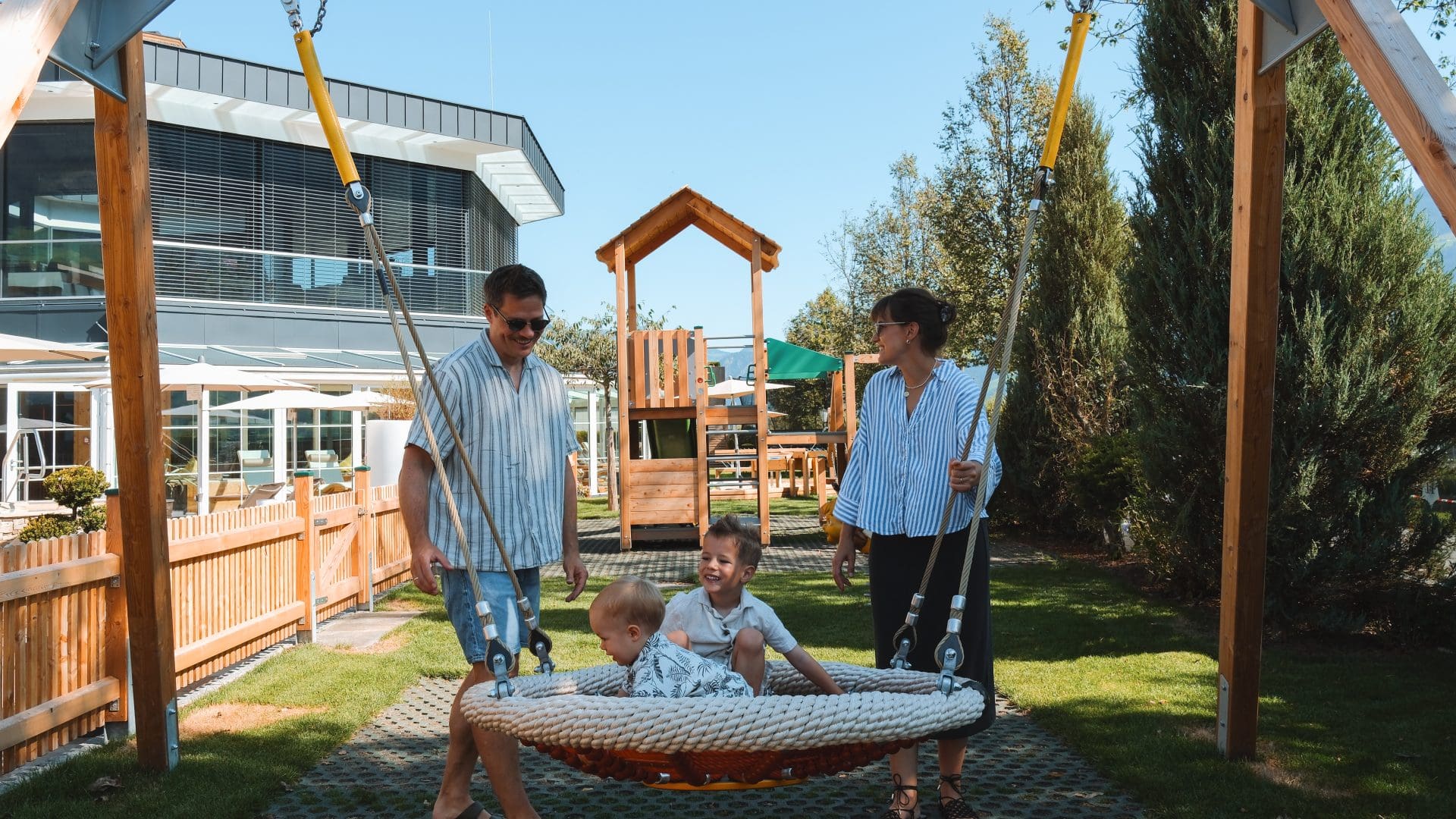 Kinder schaukeln im Familienhotel mit Spielplatz und Kinderbetreuung in Tiroler Wellnesshotels.