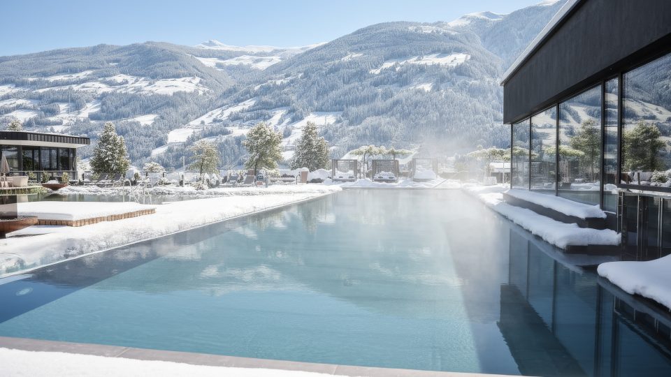 Winterliches Wellnesshotel in Tirol mit beheiztem Außenpool und Blick auf verschneite Berge.