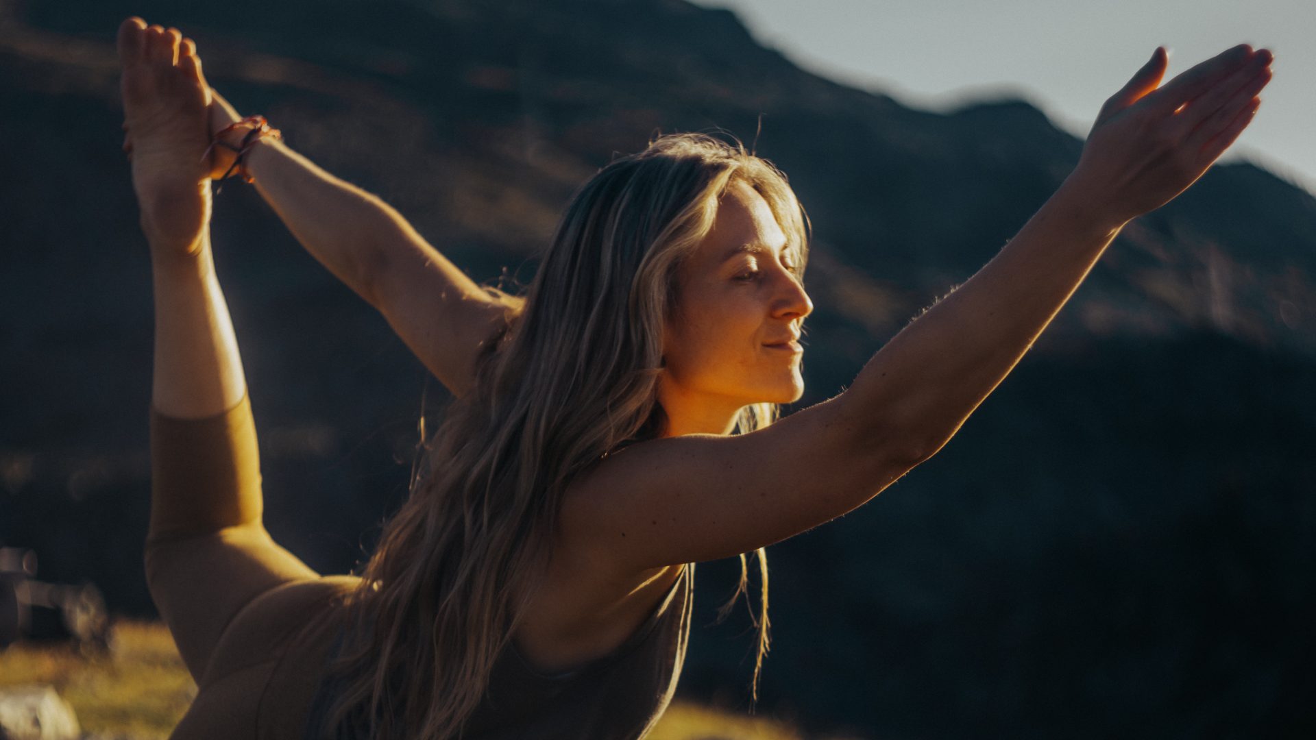 Alt Text: Frau meditiert in der Natur mit Blick auf Berge, Erholung im Tiroler Wellnesshotel.