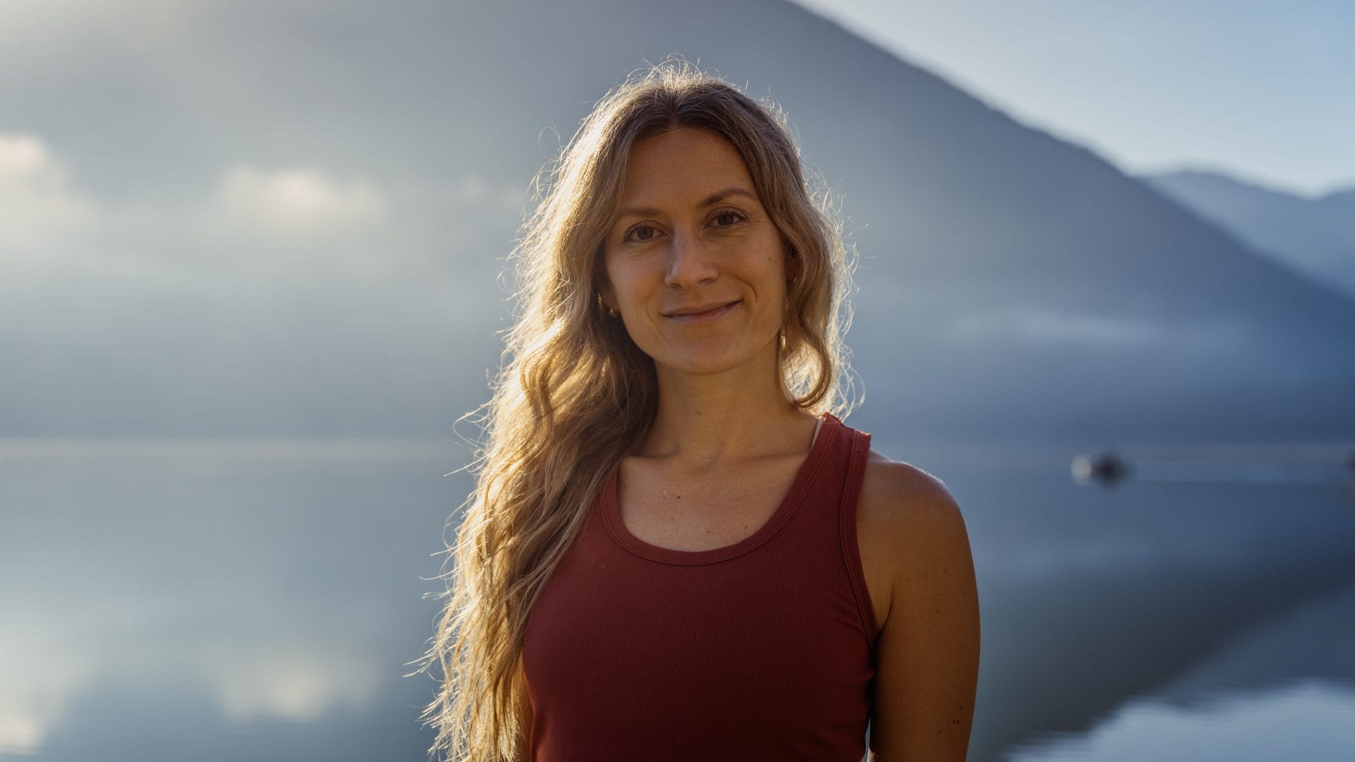 Entspannte Frau vor Tiroler Bergsee mit Wellnessatmosphäre, ideal für Erholung im Tiroler Wellnesshotel.