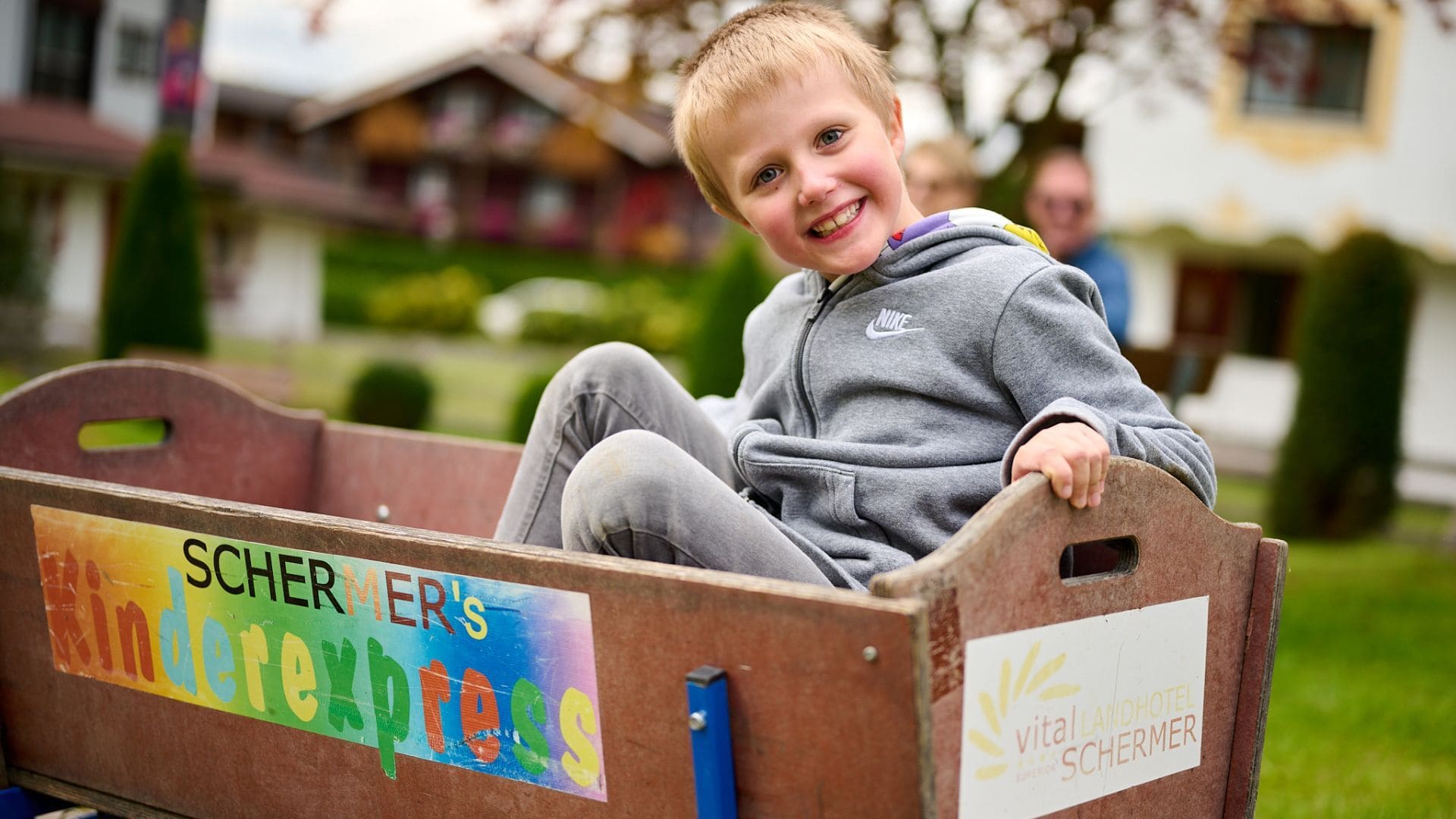 Kinder spielen glücklich im Garten eines Tiroler Wellnesshotels, ideal für Familienurlaub und Entspannung.