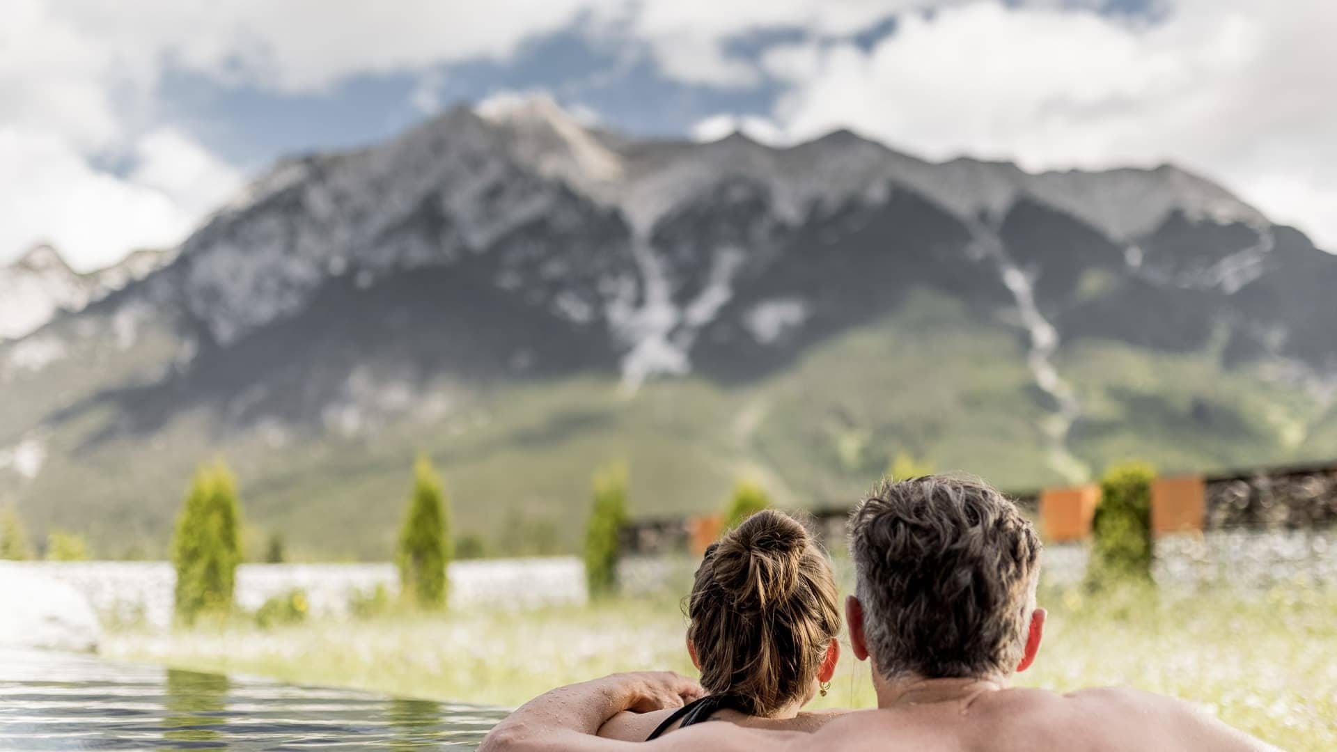 Entspannende Paare im Außenpool mit Blick auf die Tiroler Berge, ideal für Wellness und Erholung in Tirol.
