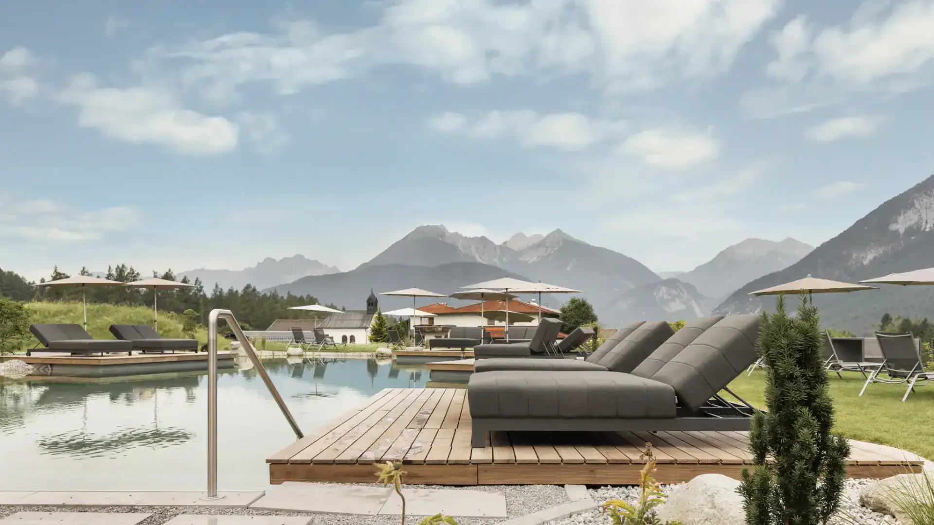 Pool mit Liegestühlen und Ausblick auf Tirols Berge, ideal für Wellnessurlaub in Tirol.