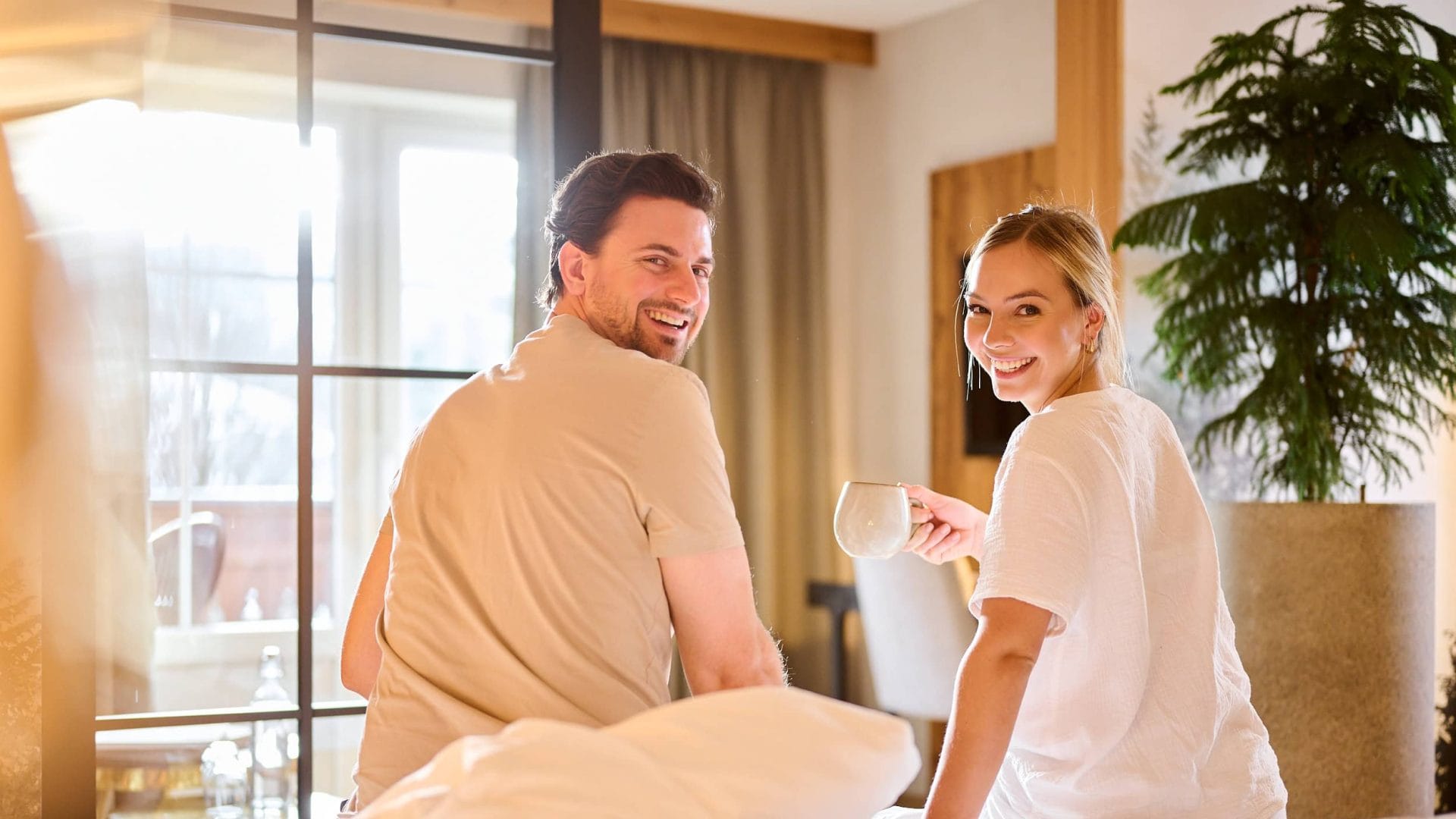 Gemütliches Paar im Hotelzimmer mit Blick auf die Natur, ideal für einen Wellnessurlaub in Tirol.
