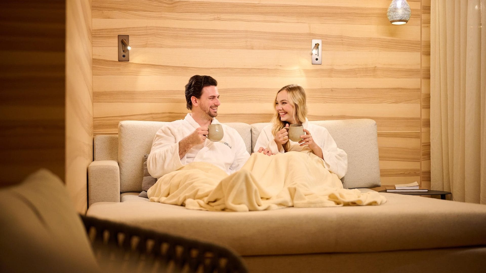 Ehepaar entspannt bei Tee im luxuriösen Hotelzimmer Tirol, Wellness, Entspannung, Alpenurlaub, Spa, romantische Auszeit, Komfort.