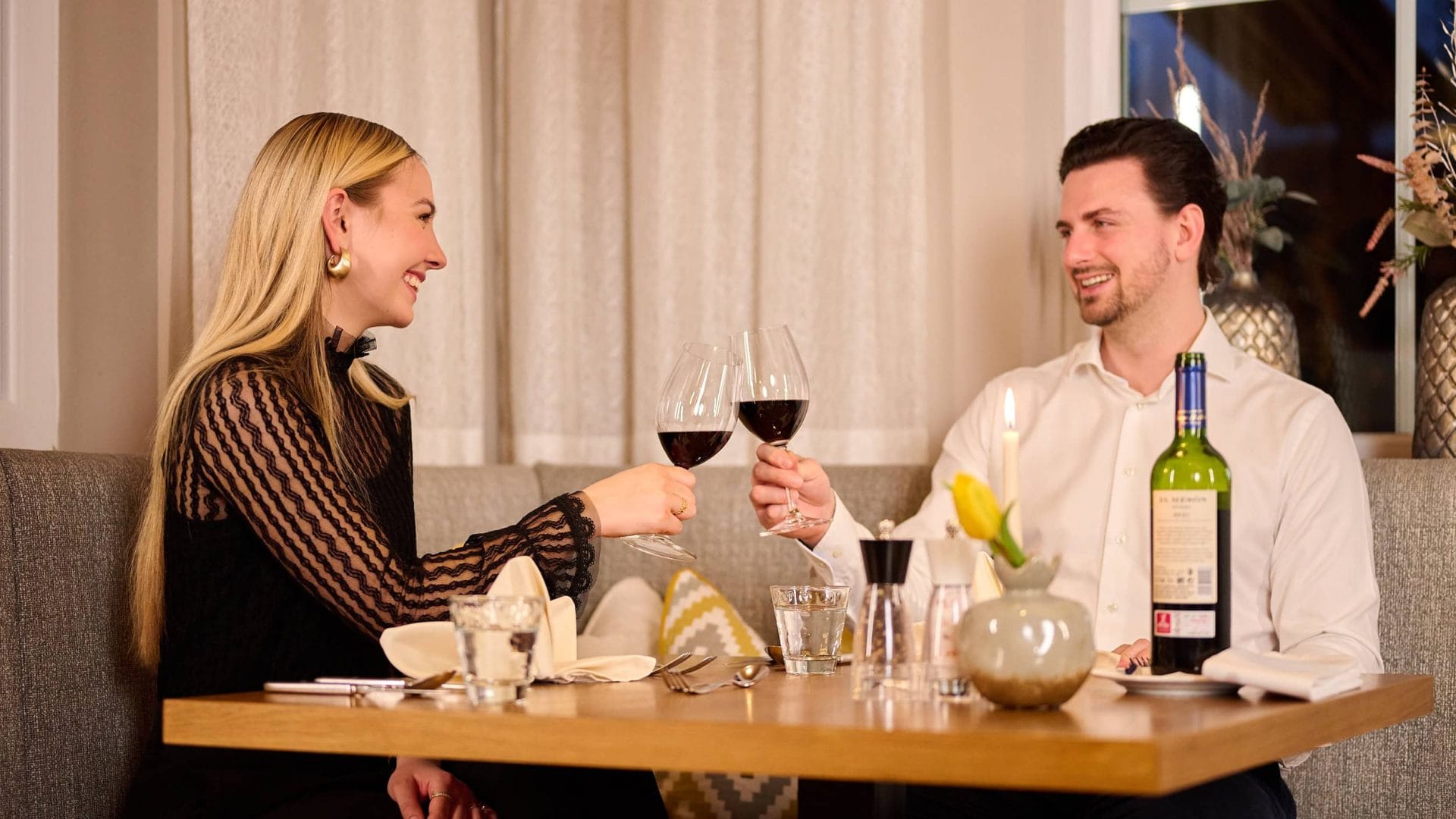 Paar beim Wein trinken im Wellnesshotel, gemütliches Dinner, romantische Atmosphäre.